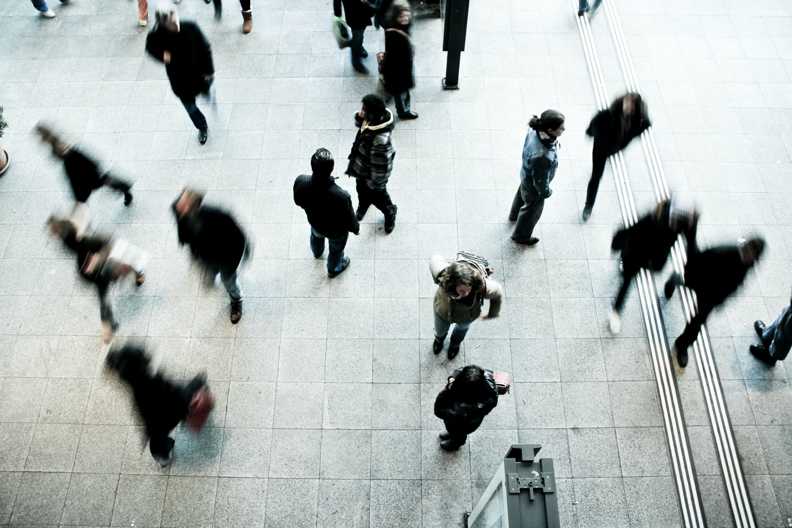People walking in a public space, blurred by their movement.