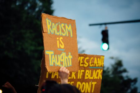 unrecognizable demonstrators showing anti racism placards during protest