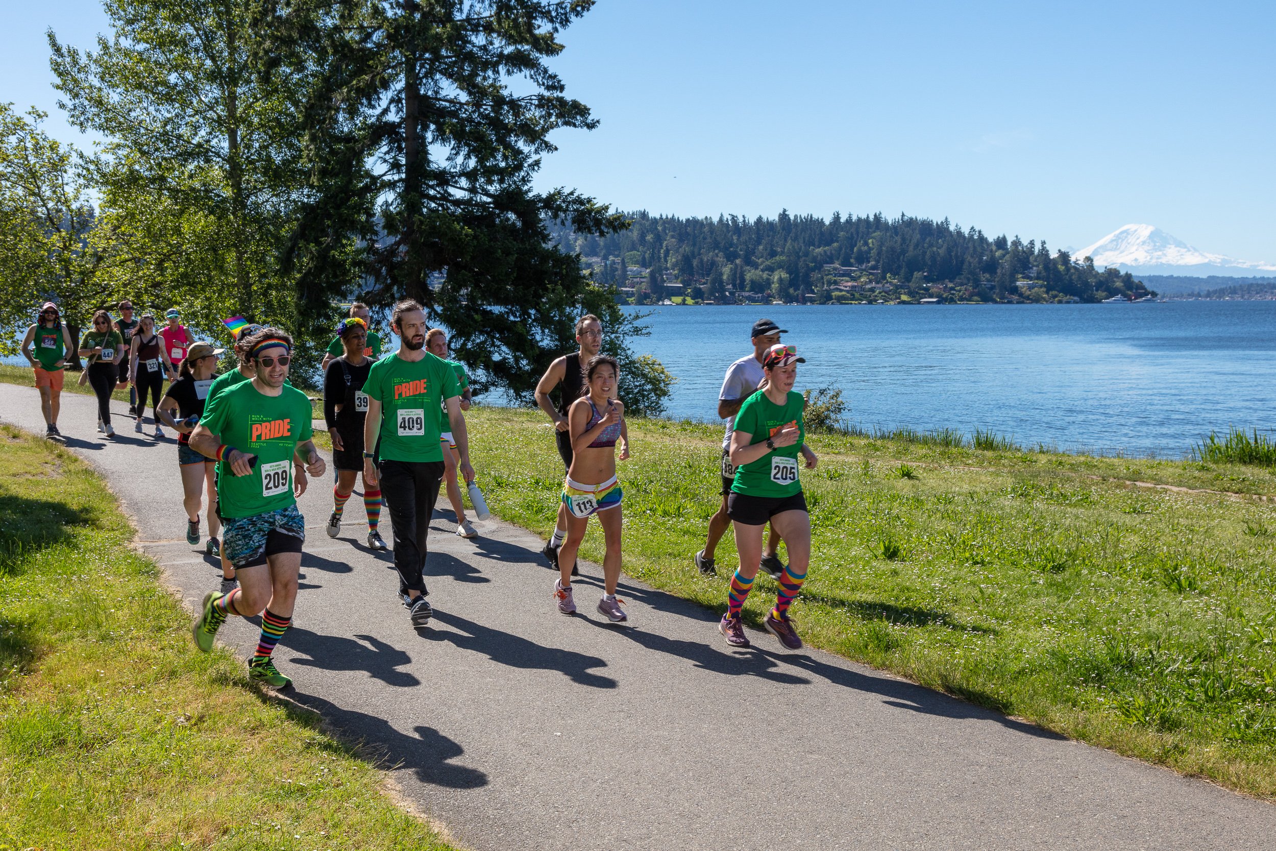 Photo of runners and walkers on a path with a lake in the background and mount rainier behind the lake