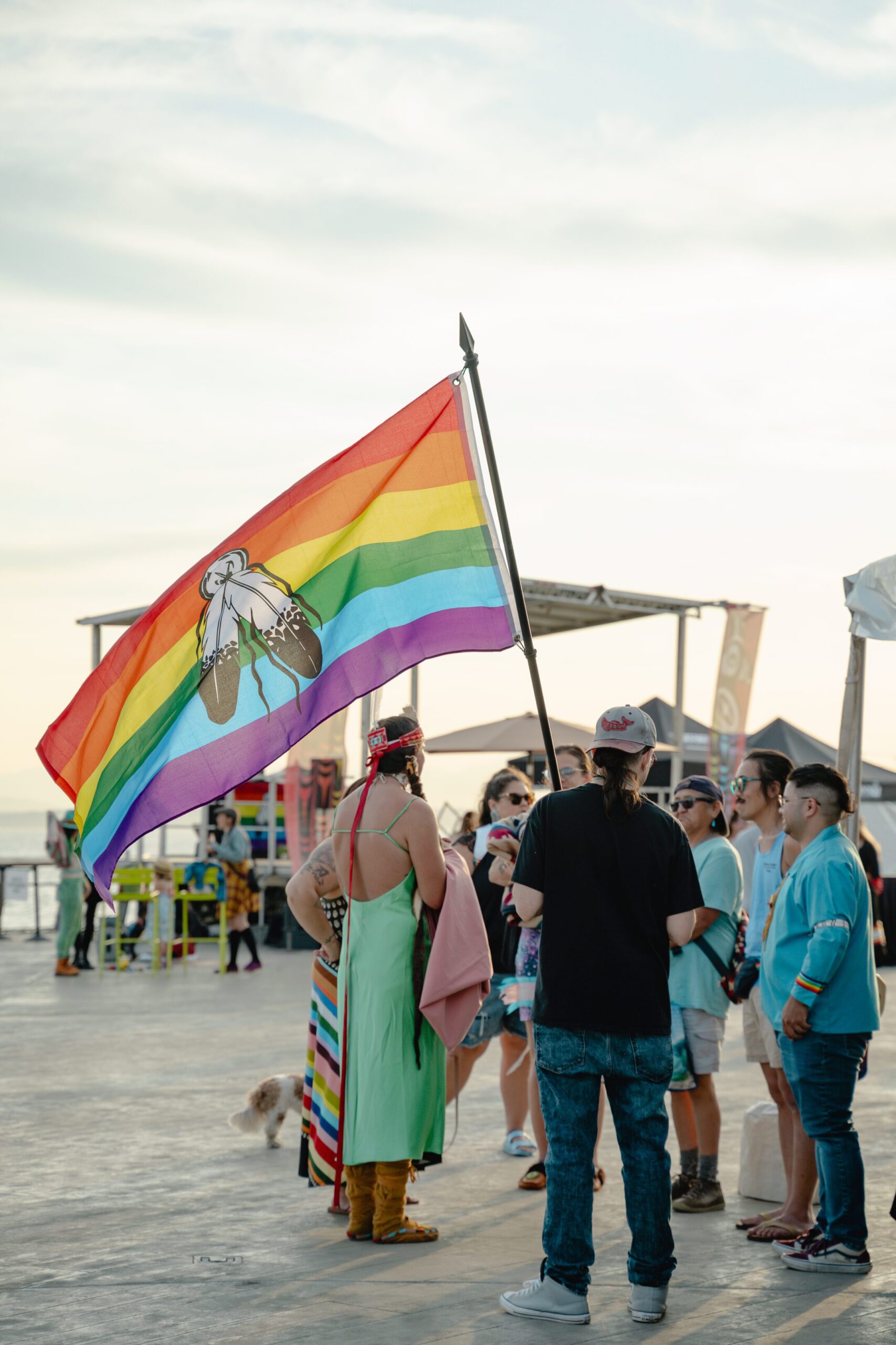 Photo of Indigiqueer 2023 - group of people holding a rainbow flag with indigenous head dress