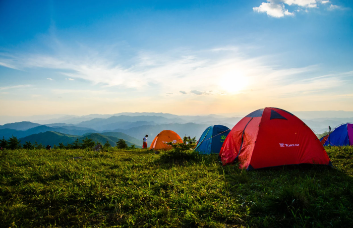 Photo of some tents pitched on top of a ridge overlooking the mountains below
