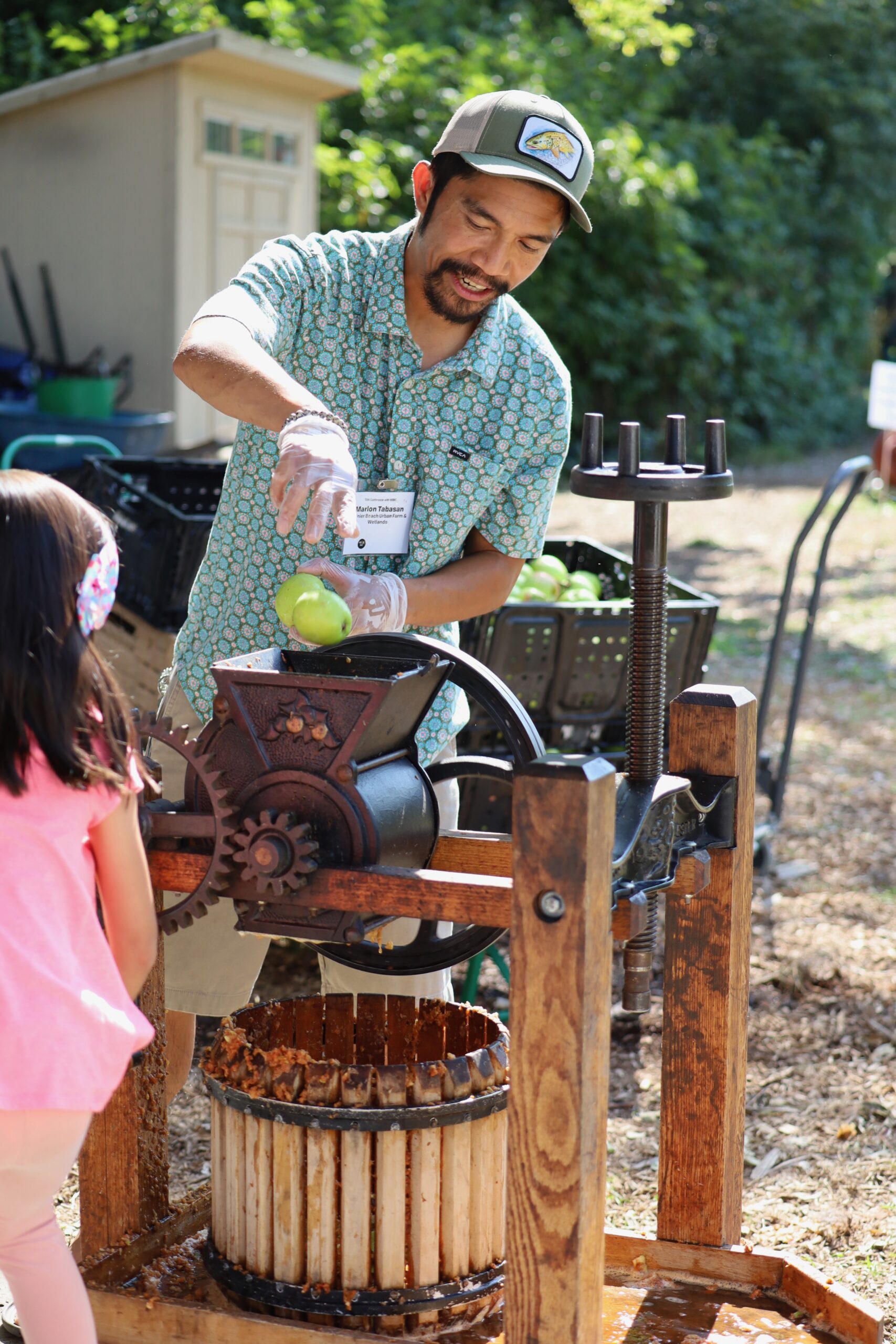 Photo of a man pressing apples as a child watches