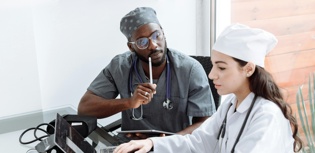 Photo of two people dressed in scrubs working on a computer